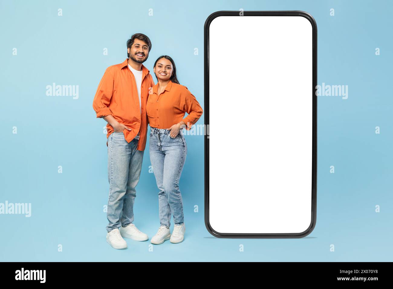 Couple debout avec un smartphone géant sur fond bleu Banque D'Images