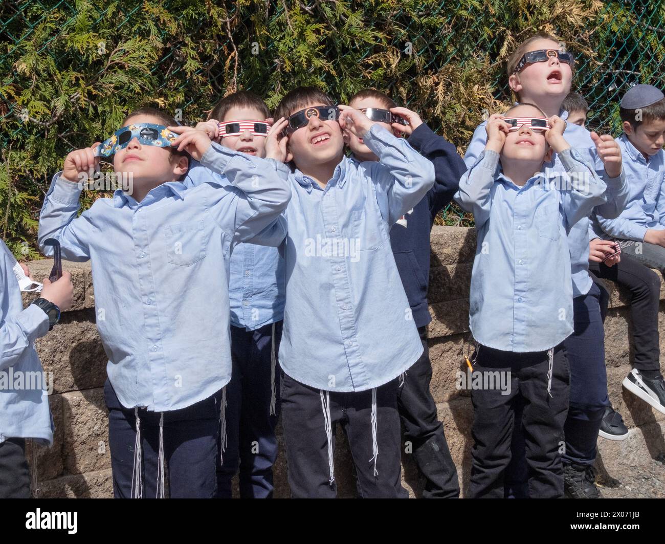 Un groupe de garçons juifs orthodoxes regarde l'éclipse solaire de 2024 depuis la cour de leur yeshiva. Dans le comté de Rockland, New York. Banque D'Images