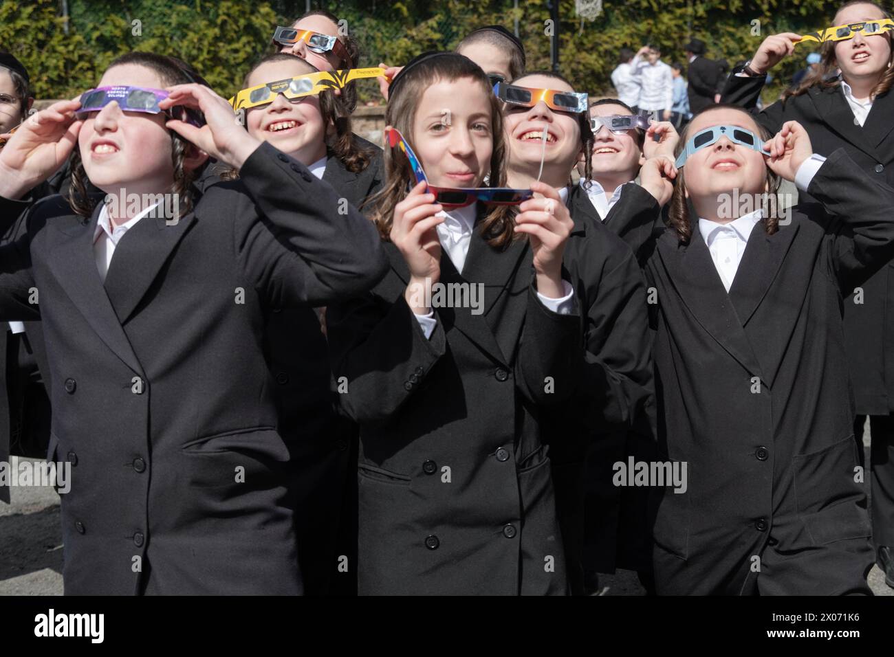 Un groupe de garçons juifs orthodoxes regarde l'éclipse solaire de 2024 depuis la cour d'école de leur école paroissiale. Dans le comté de Rockland, New York. Banque D'Images