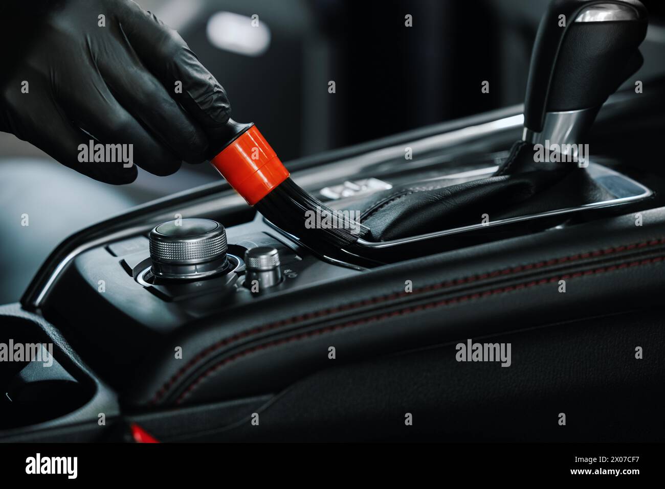 nettoyage de l'intérieur d'une voiture. un gros plan de la main avec une brosse nettoie la poussière de la console centrale Banque D'Images