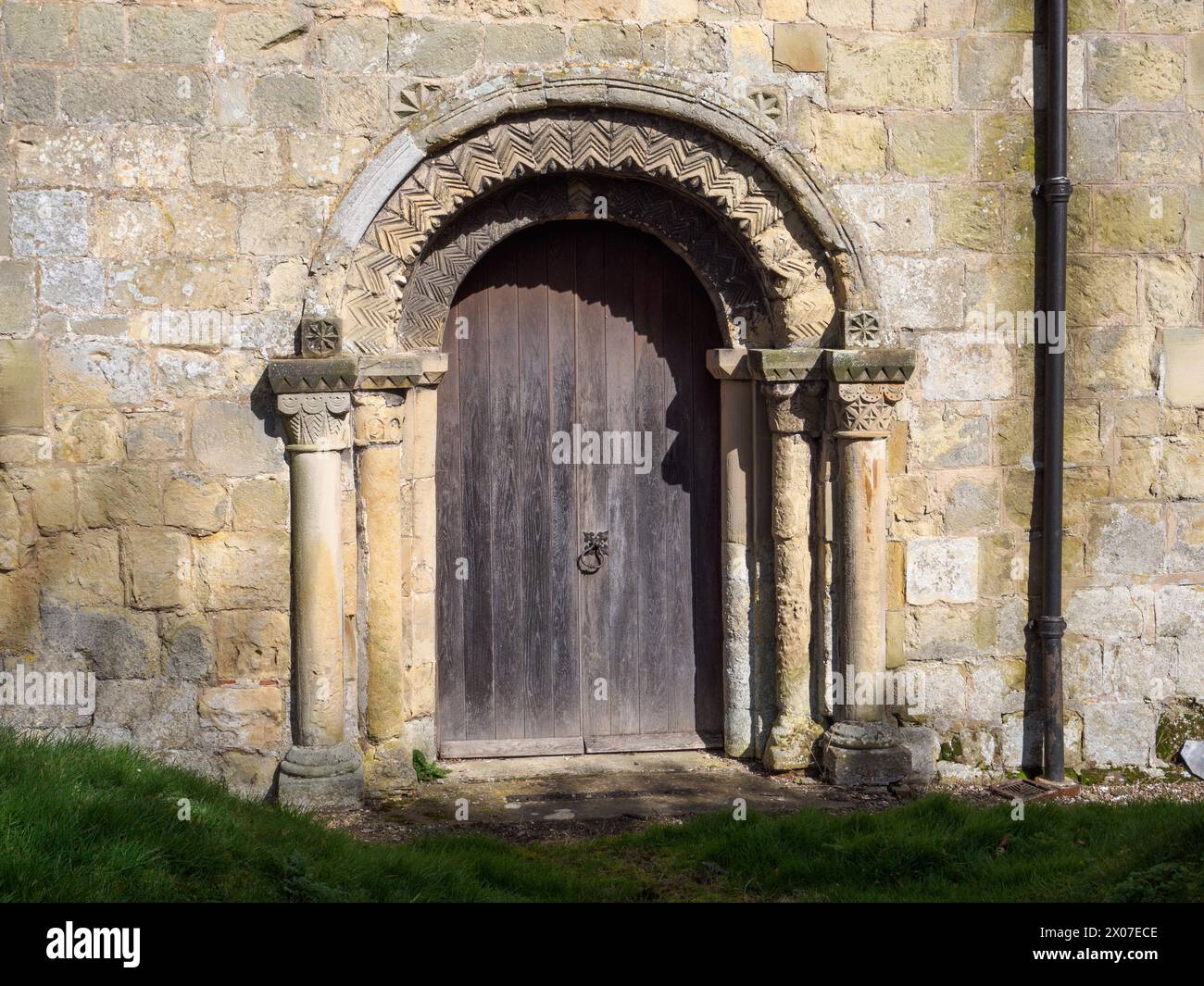 La porte sud normande de All Saints North Dalton avec capital gauche inhabituel de demi-figures sous des arches Banque D'Images