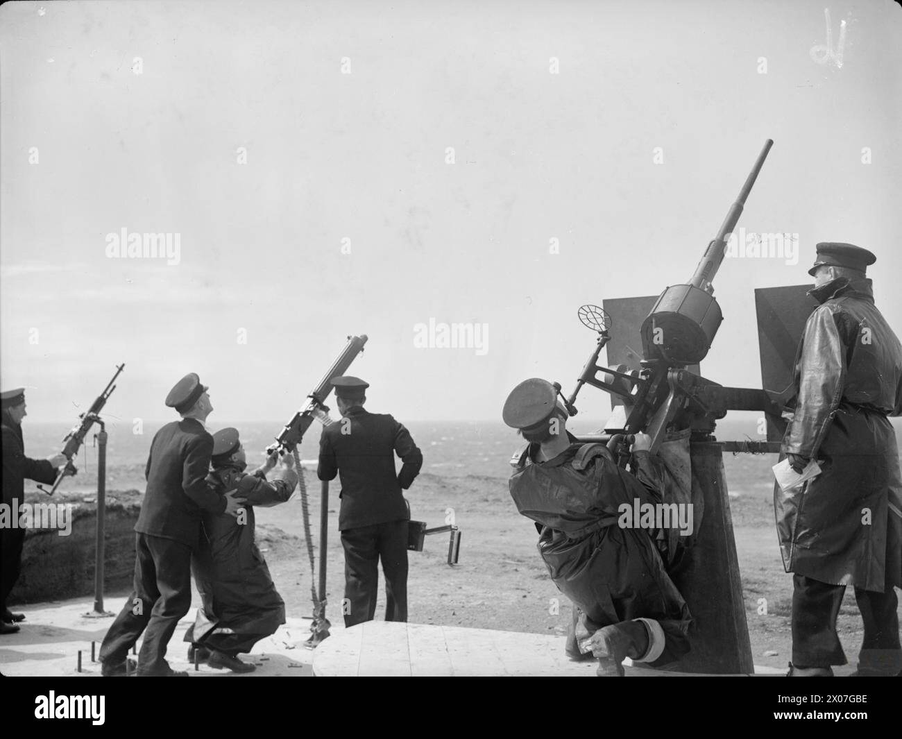 LES MARINS S'ENTRAÎNENT POUR LES COMBATS TERRESTRES. DU 1ER AU 3 JUIN 1942, NORTHERN RANGE, ORKNEYS. UNE ÉQUIPE DE DÉBARQUEMENT DU HMS WHEATLAND PRATIQUANT AVEC DES FUSILS, DES BAÏONNETTES, DES ARMES AUTOMATIQUES ET DES CANONS ANTIAÉRIENS SUR TERRE. - Un Oerlikon sur la gauche et un pistolet Hotchkiss en action alors qu'un avion vole au-dessus de la tête tirant un drone Banque D'Images