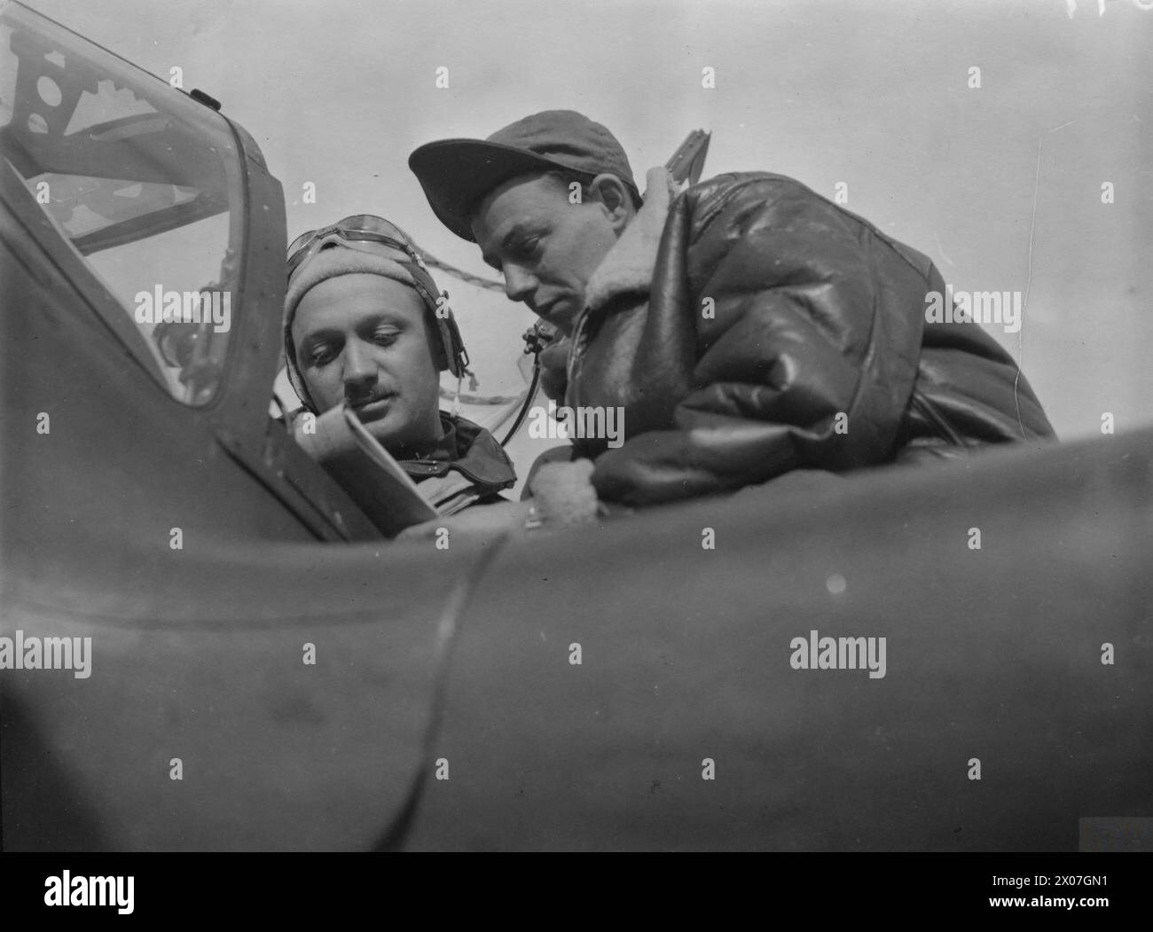 HUITIÈME FORCE AÉRIENNE DES ÉTATS-UNIS EN GRANDE-BRETAGNE, 1942-1945 - le capitaine Carl E. Jackson et le sergent technique John P. Duffey, tous deux du 20th Fighter Group, se concertent à la base aérienne de Kings Cliffe, octobre 1943.légende imprimée jointe à l'impression : 'Lightnings Attack Northern France. Les éclairs P-38 polyvalents, faisant clignoter leur puissance à travers la Manche pour la première fois dans un rôle de combat, apportent une nouvelle phase sérielle dans le théâtre des opérations européen. Des pilotes bien entraînés - certains d'entre eux déjà expérimentés dans les autres théâtres de guerre - et des équipages au sol jurent devant leurs navires. Du briefing R Banque D'Images