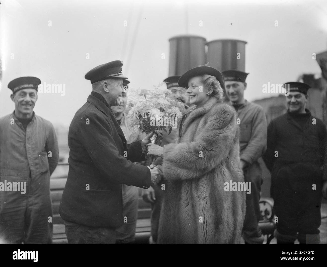 En 1941, l'actrice Evelyn Laye visite un port naval et reçoit un bouquet d'un membre de la compagnie du navire. Banque D'Images