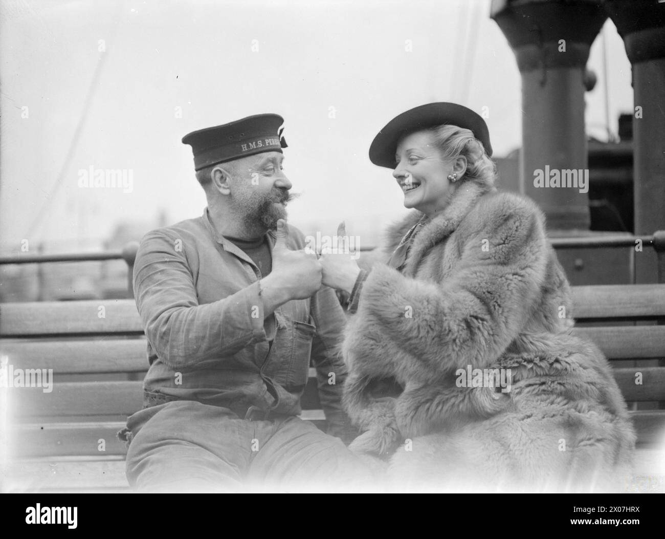 En 1941, l'actrice Evelyn Laye a visité un port naval et est photographiée avec un marin barbu, les deux donnant le geste du pouce vers le haut. Banque D'Images