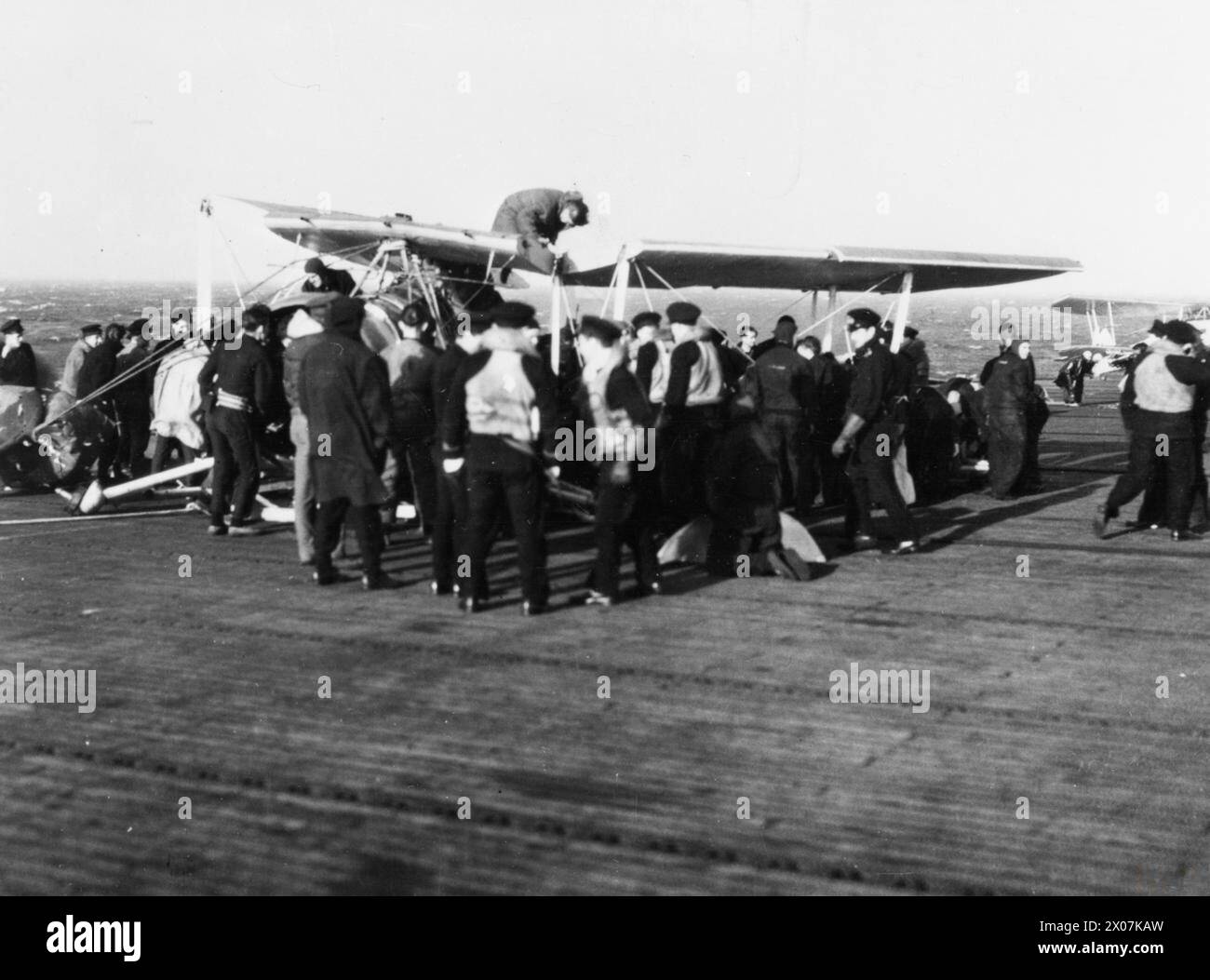 Une photographie à bord du HMS Striker en 1944 montrant les conséquences d'un atterrissage accidentel. Les avions endommagés sont dépouillés de pièces utiles et jetés à la mer, illustrant les opérations de porte-avions pendant la IIe Guerre mondiale Banque D'Images