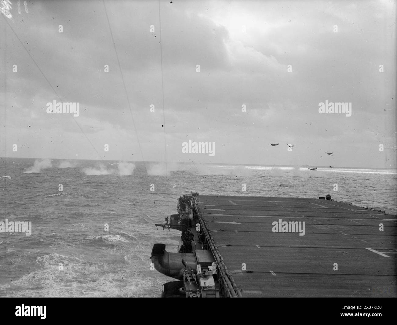 LE ROI FAROUK VISITE LE PORTE-AVIONS D'ESCORTE BRITANNIQUE. MARS 1945, À BORD DU HMS HUNTER, ALEXANDRIE, ÉGYPTE. - Les feux de mer du CHASSEUR effectuant une attaque à la bombe sur une cible remorquée à l'est du porte-avions d'escorte Banque D'Images