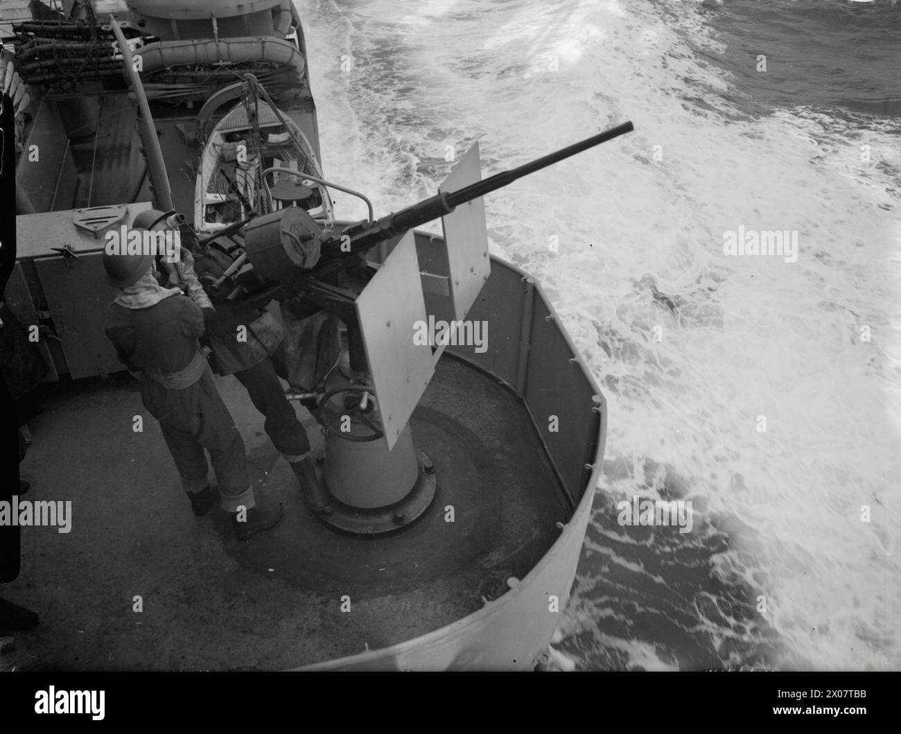 Un artilleur Oerlikon de 20 mm sur le HMS Dido a reçu une lumière d'un collègue entre les attaques à la bombe dans l'est de la Méditerranée pendant les opérations de la Royal Navy. Banque D'Images