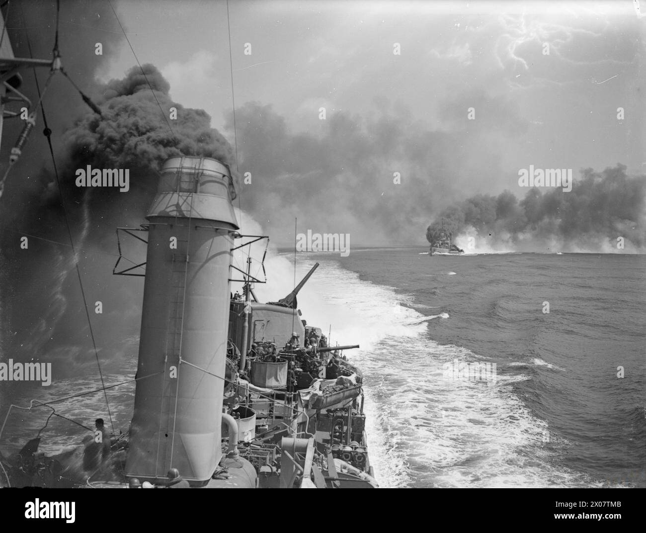 Le 18 mai 1944, le HMS Dido bombarde des cibles ennemies près de Gaeta, en Italie, tandis que l'USS Mackenzie et l'Ordnaux projettent le croiseur avec de la fumée en Méditerranée. Banque D'Images