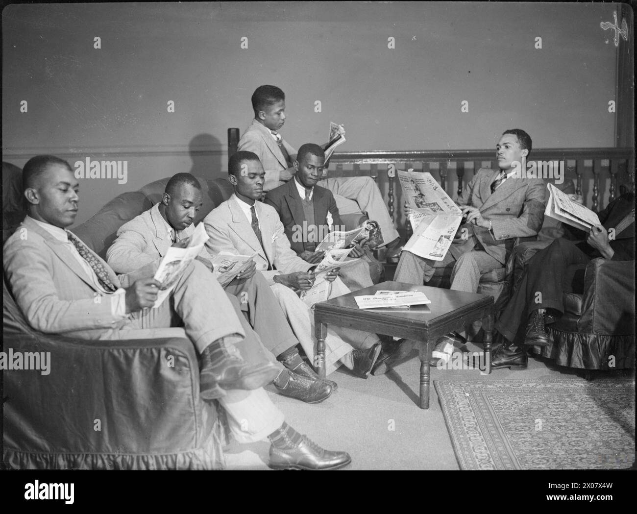 Des techniciens jamaïcains arrivent en Grande-Bretagne en 1941, assis dans le salon de West India House lisant des journaux et des magazines tout en se préparant à se former et à travailler dans des usines du Merseyside. Banque D'Images Des techniciens jamaïcains arrivent en Grande-Bretagne en 1941, assis dans le salon de West India House lisant des journaux et des magazines tout en se préparant à se former et à travailler dans des usines du Merseyside. Banque D'Images