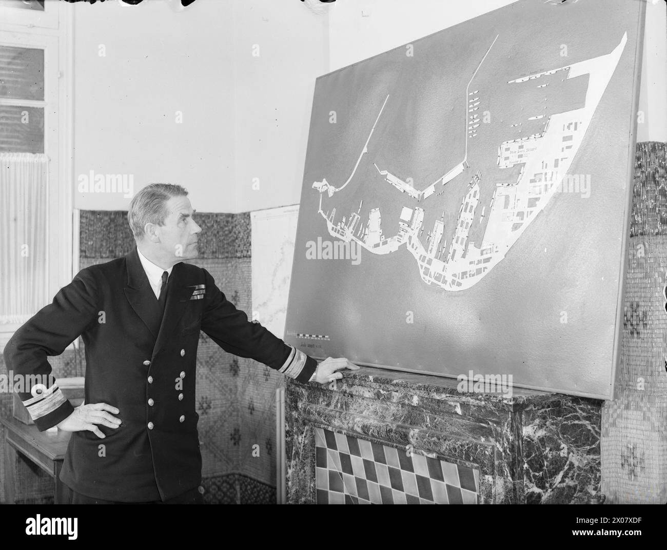 Entre le 18 et le 23 février 1943 à Alger, le commodore J. A. V. Morse, en charge de l'accostage des convois, est montré en train de consulter la carte d'accostage des quais pour coordonner efficacement le retour des navires à la mer. Banque D'Images