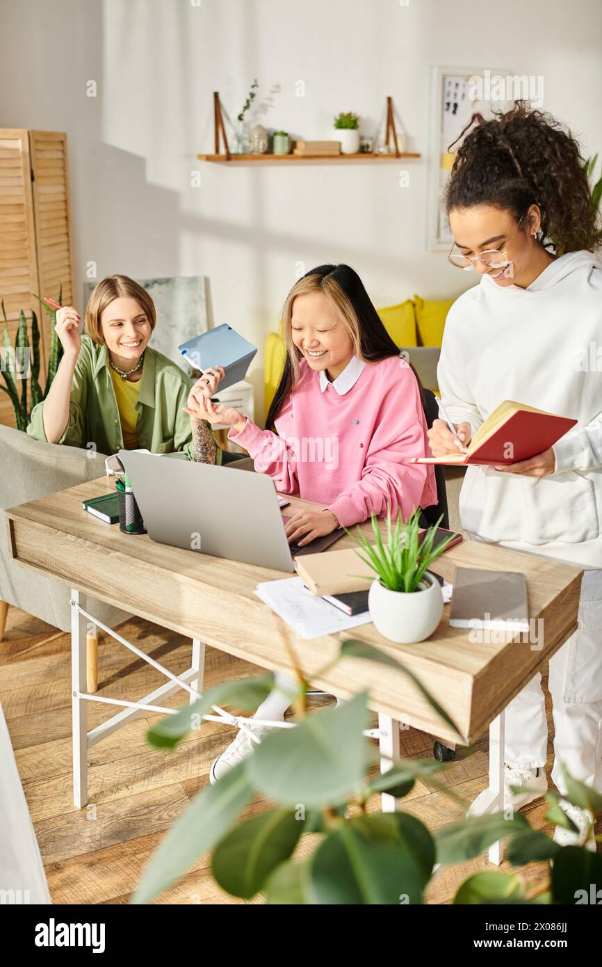 Un groupe diversifié d'adolescentes se sont rassemblées autour d'un ordinateur portable, engagées dans l'étude et la promotion de l'amitié dans le confort de la maison. Banque D'Images