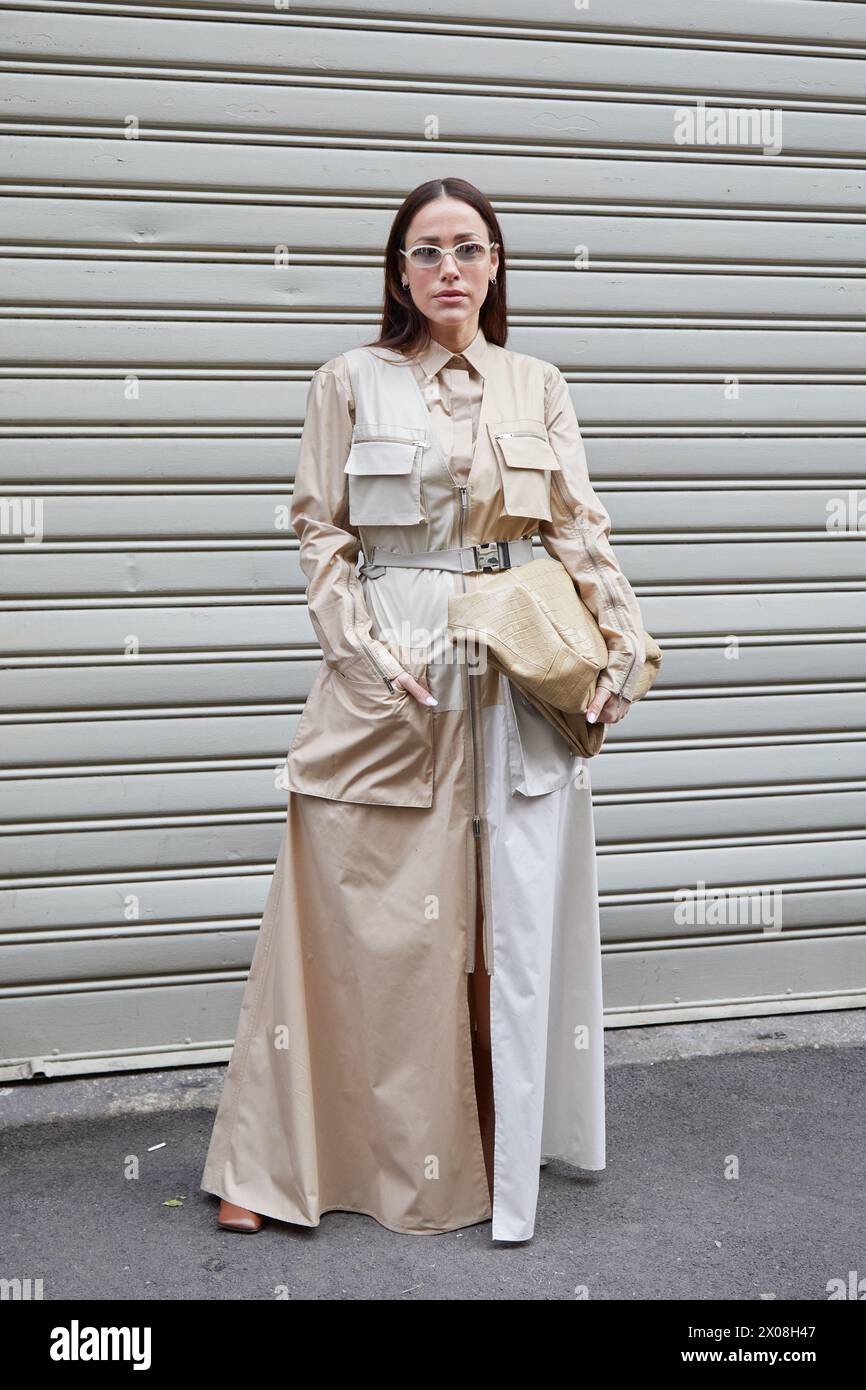 MILAN, ITALIE - 21 FÉVRIER 2024 : femme avec un long manteau beige et un sac avant le défilé Iceberg, dans le style de la semaine de la mode de Milan Banque D'Images
