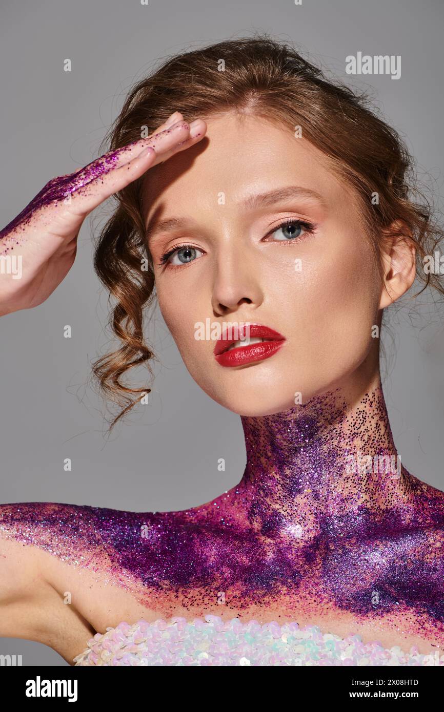 Une jeune femme à la beauté classique pose dans un studio recouvert de peinture violette et rose, dégageant une élégance éthérée. Banque D'Images