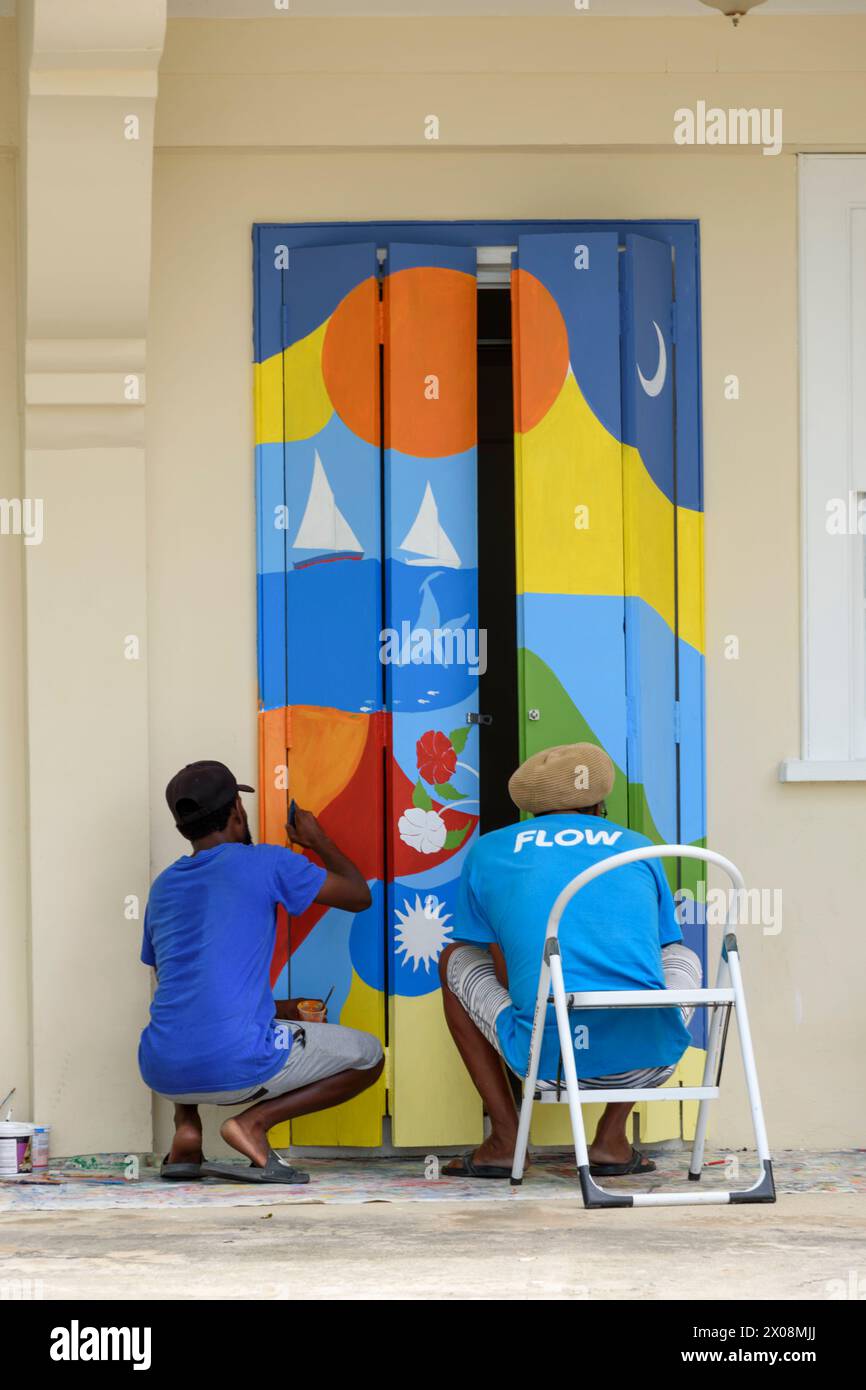 Deux hommes locaux peignant une peinture murale colorée sur une porte, Port Elizabeth, Bequia Island, St Vincent et les Grenadines, Caraïbes Banque D'Images