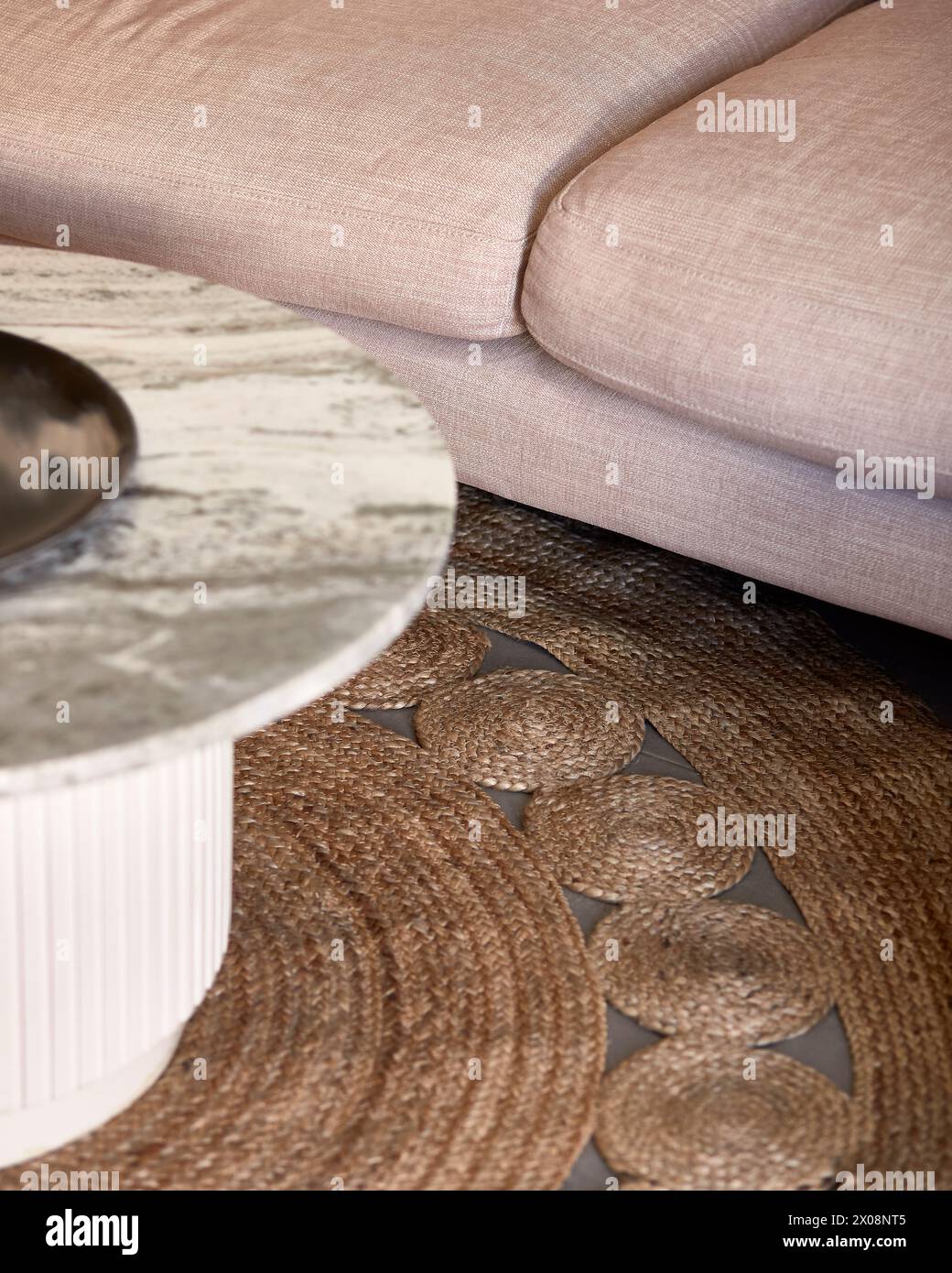 Un gros plan d'un salon moderne avec une section d'un canapé rose confortable et une table basse décorative en marbre avec un bol métallique, sur une texture Banque D'Images