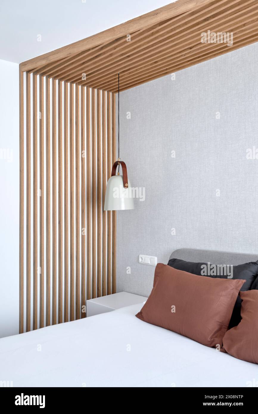 Intérieur moderne de la chambre avec design mural à lamelles en bois et élégante lampe suspendue Banque D'Images