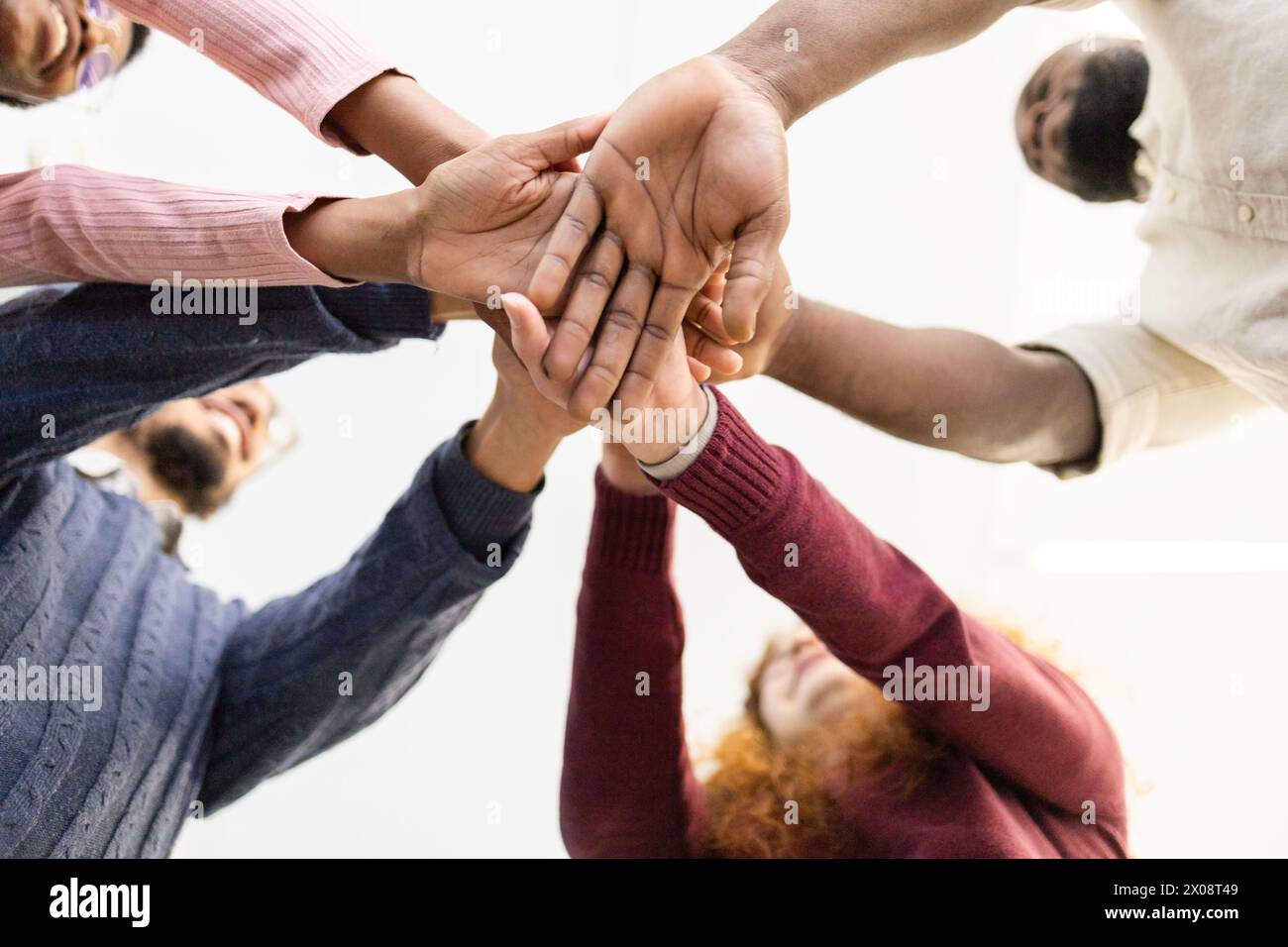 d'en bas, un groupe diversifié et méconnaissable de personnes empilent leurs mains dans une démonstration d'unité, de travail d'équipe et de collaboration. Ils examinent chacun d'eux Banque D'Images