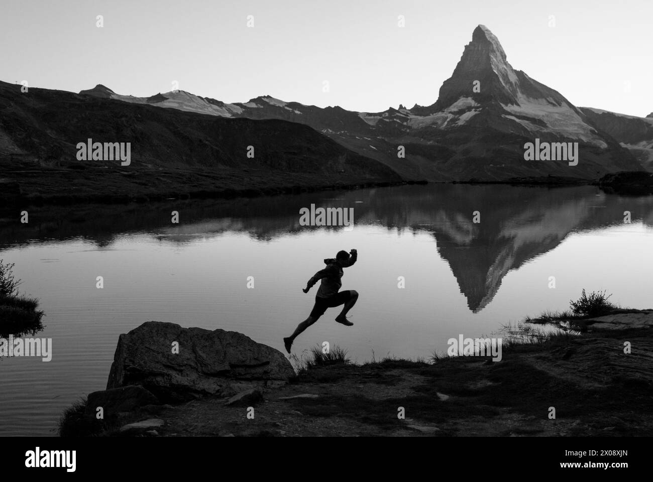 Une silhouette dynamique d'une personne sautant par Stellisee avec l'emblématique Cervin et son reflet comme une superbe toile de fond monochrome dans la Suisse Banque D'Images