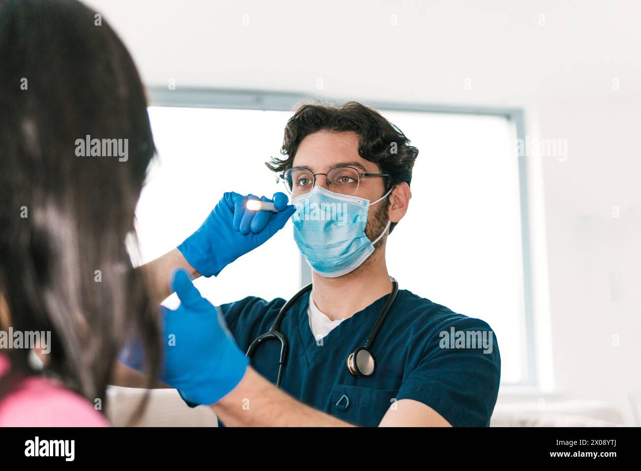 Un médecin spécialisé examine la gorge d’un patient à l’aide d’une lampe médicale, une partie essentielle d’un bilan ORL de routine Banque D'Images