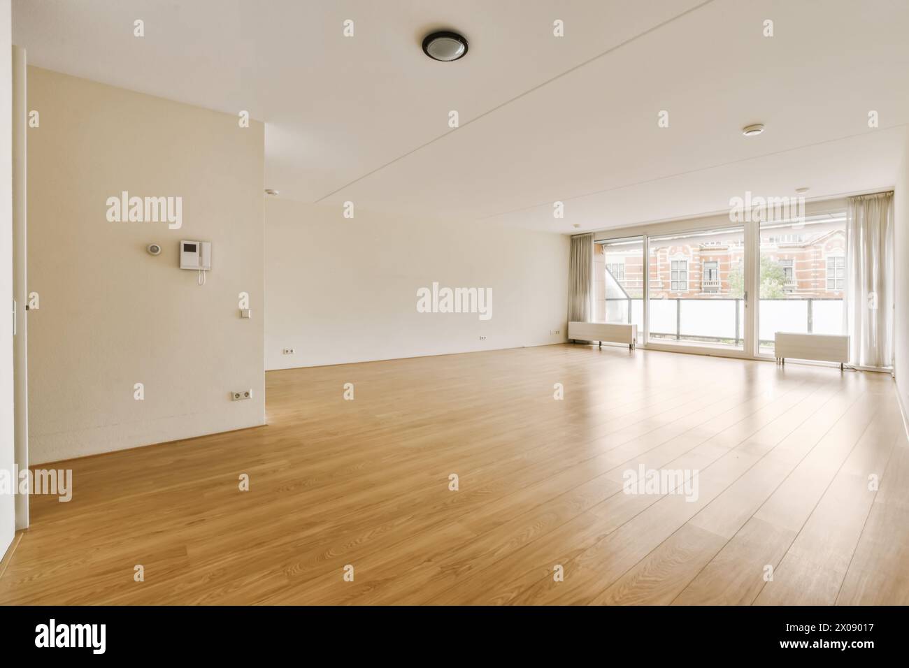 Cette chambre spacieuse et bien éclairée dispose d''une grande fenêtre avec des rideaux et d''un parquet ciré. Banque D'Images