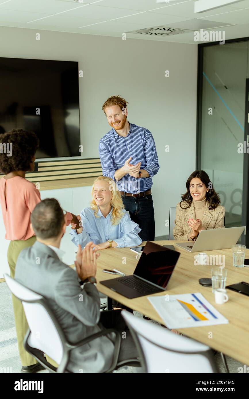 Groupe multiethnique de professionnels qui brainstorment autour d'une table de conférence dans un bureau bien éclairé. Banque D'Images