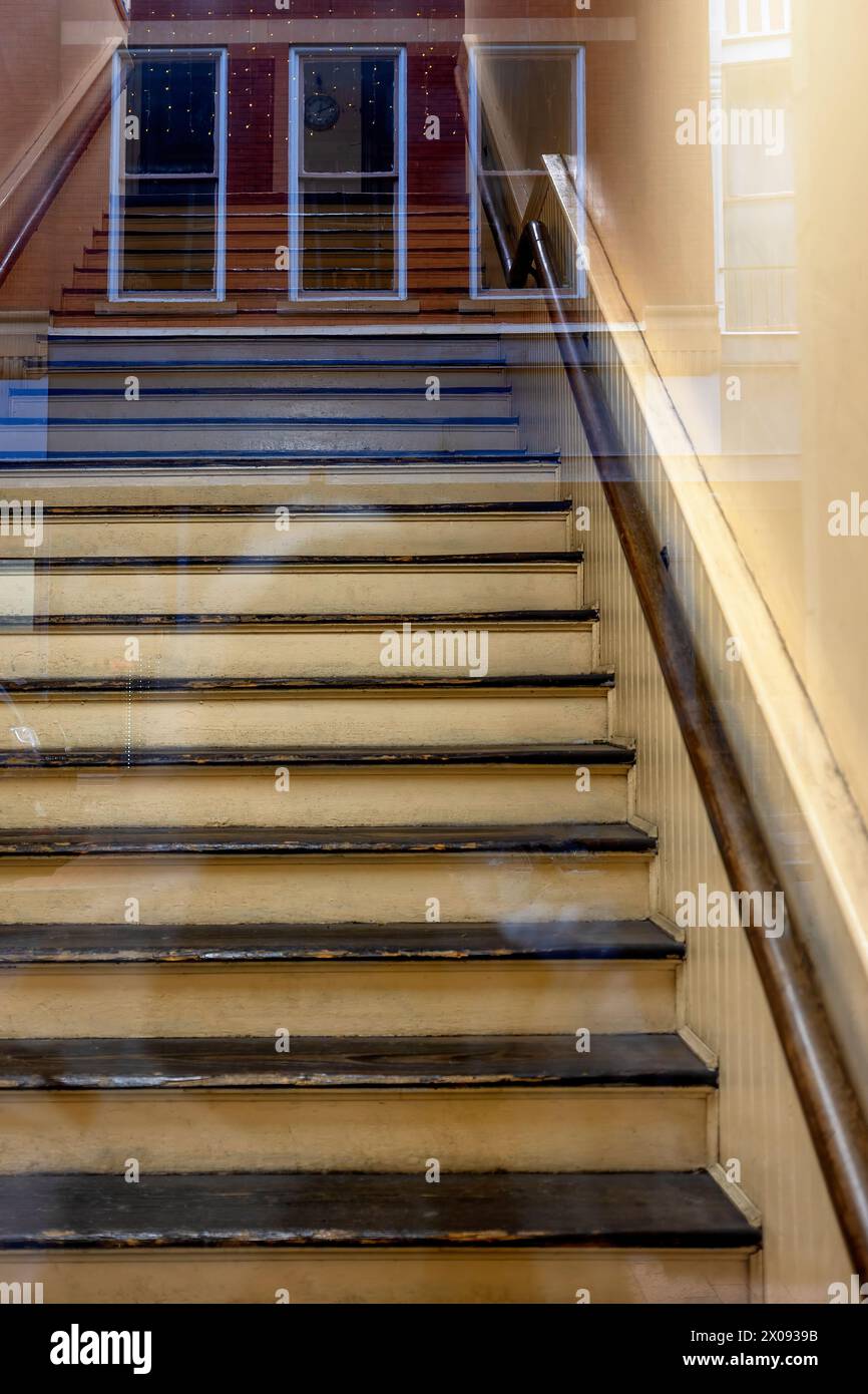 Vue abstraite regardant à travers une porte en verre réfléchissante qui mène à un escalier. Banque D'Images