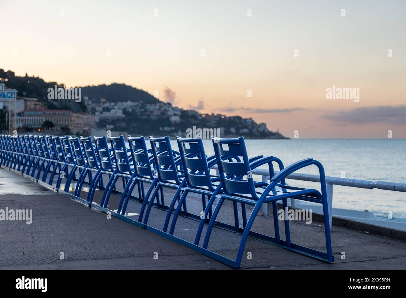 Chaises bleues le long de la Promenade des Anglais, Nice France, au lever du soleil Banque D'Images