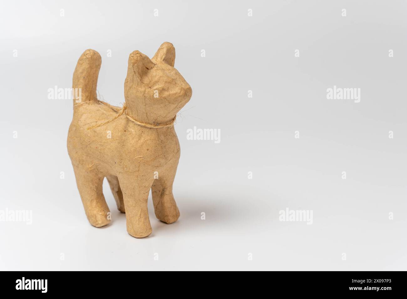 Une sculpture réaliste d'un chat en papier mâché, magnifiquement conçue avec des détails complexes. Le chat est placé sur un fond blanc propre, fournissant amplement Banque D'Images