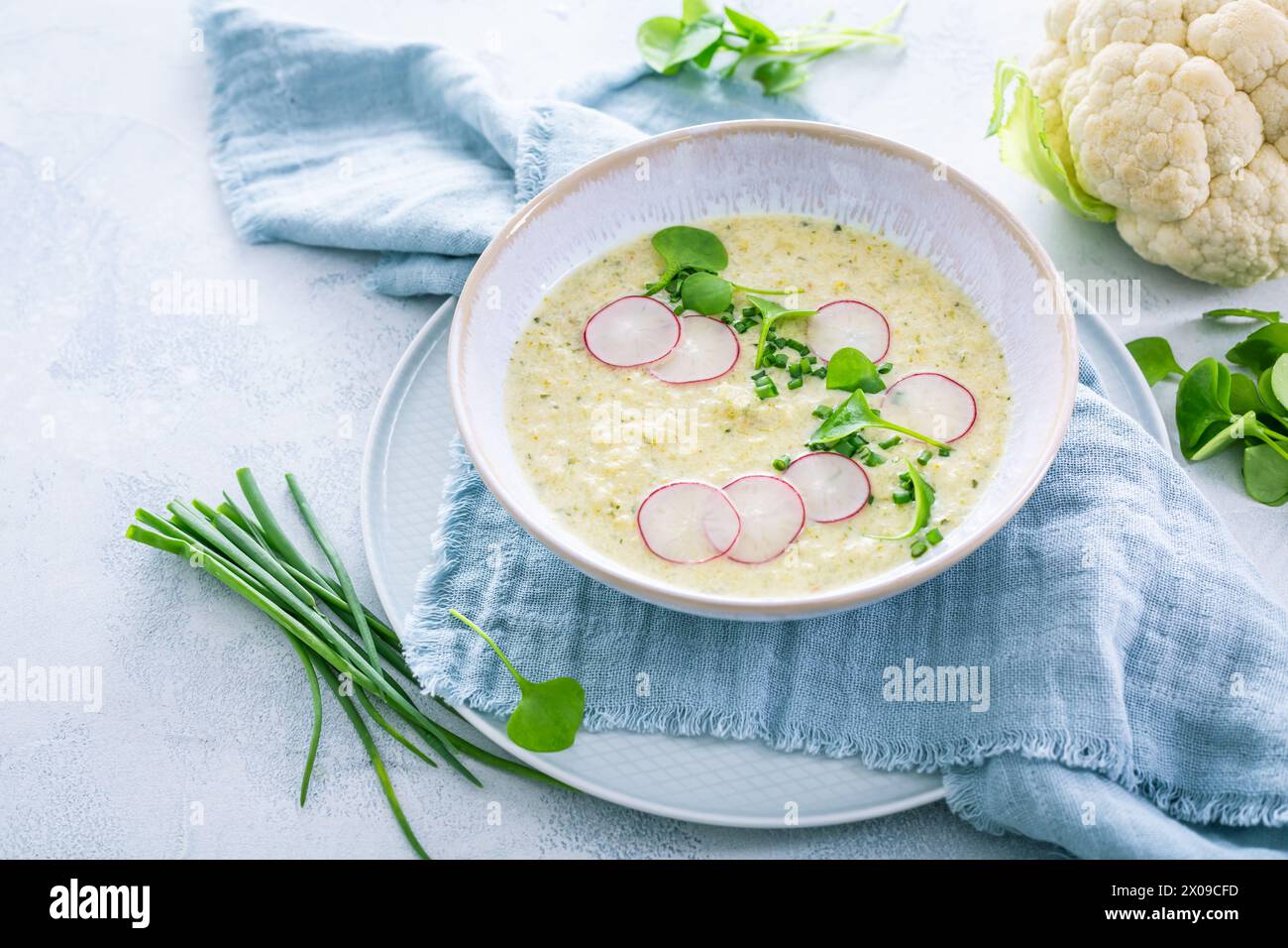 Soupe crémeuse de chou-fleur blanche avec radis et ciboulette, nourriture saine avec des herbes Banque D'Images Soupe crémeuse de chou-fleur blanche avec radis et ciboulette, nourriture saine avec des herbes Banque D'Images