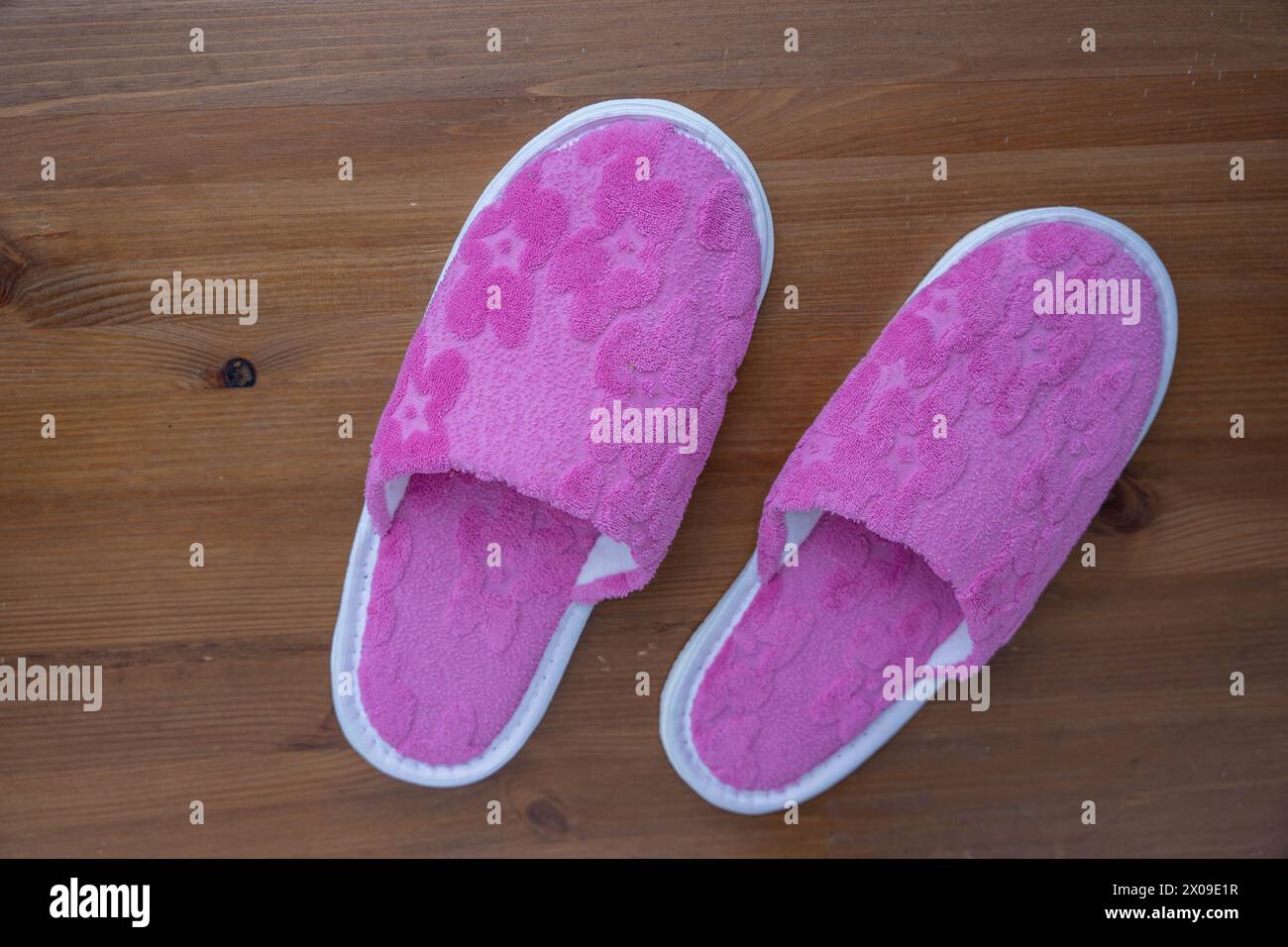 Une paire de pantoufles roses posées paisiblement sur un plancher en bois, créant une scène simple mais confortable. Banque D'Images