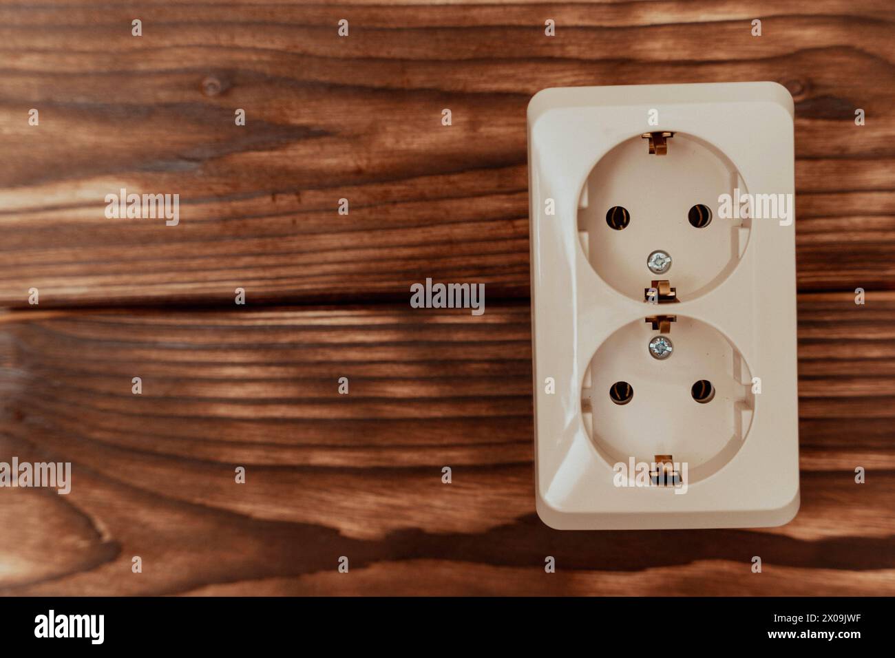 Une prise électrique est installée sur un mur en bois, fournissant un point d'accès à l'électricité dans une pièce. Banque D'Images