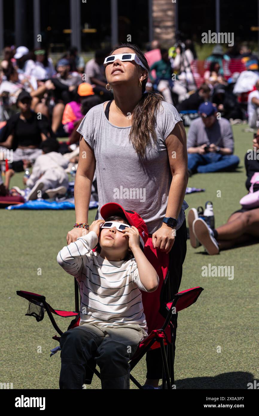 Atlanta, GA / USA - 8 avril 2024 : mère et fils regardent à travers des lunettes spéciales pour voir l'éclipse solaire totale lors d'une fête de montre le 8 avril 2024. Banque D'Images