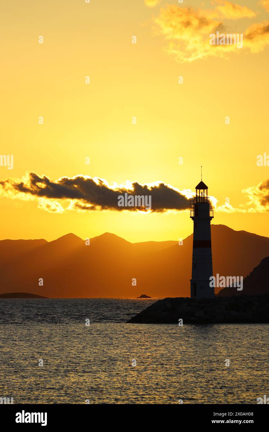 Paysage marin au soleil. Phare et croisières sur la côte. Ville balnéaire de Turgutreis et soleil spectaculaire Banque D'Images