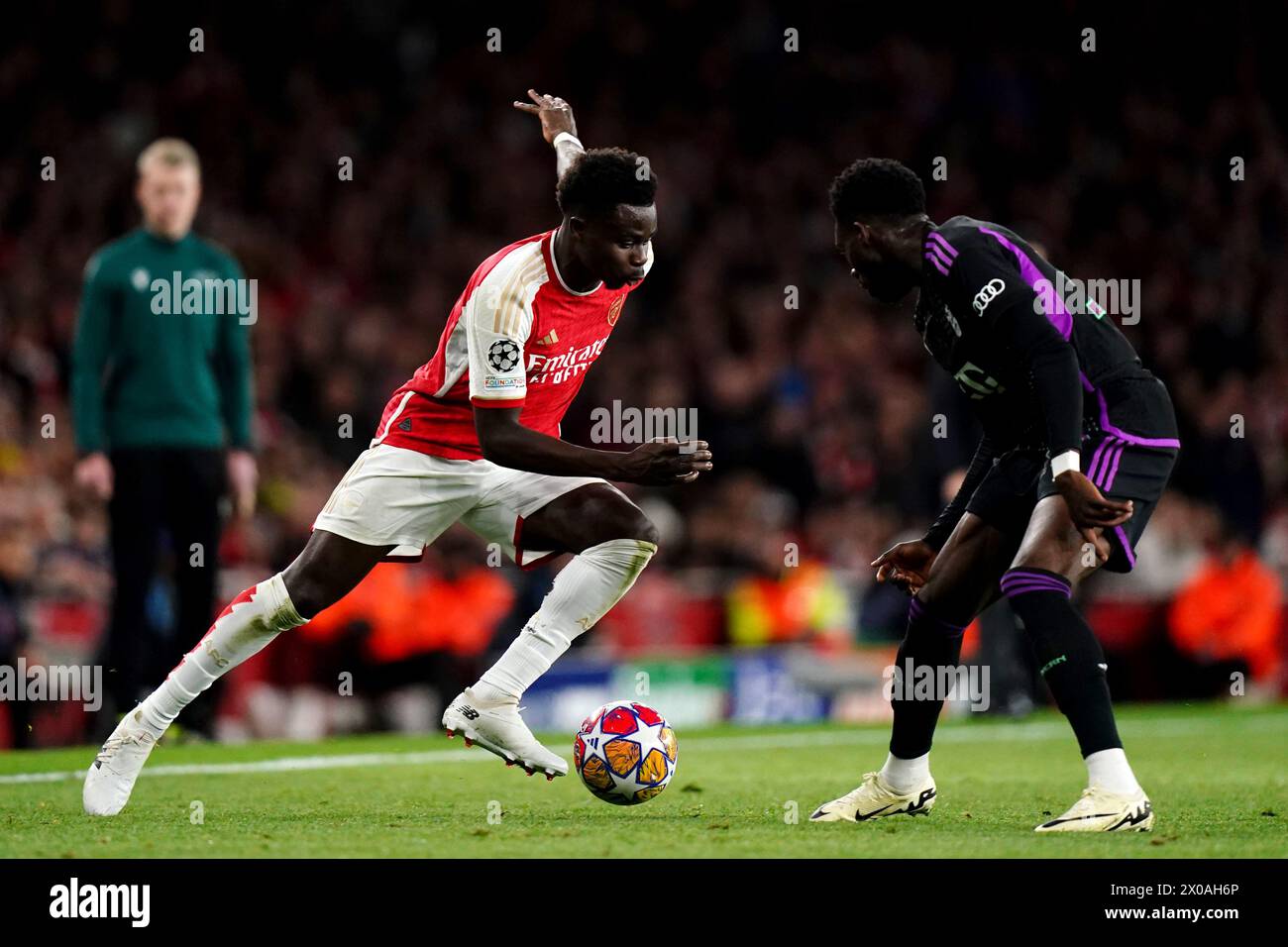 Bukayo Saka d'Arsenal (à gauche) court à Alphonso Davies du Bayern Munich pendant le quart de finale de l'UEFA Champions League, match de première manche à l'Emirates Stadium de Londres. Date de la photo : mardi 9 avril 2024. Banque D'Images