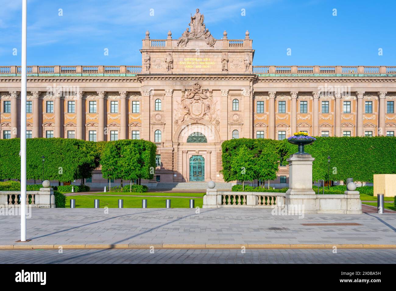 La Chambre du Parlement de Stockholm, en Suède, baignée de soleil avec un ciel bleu clair en arrière-plan, met en valeur son élégante architecture néoclassique et son environnement paysager. Banque D'Images