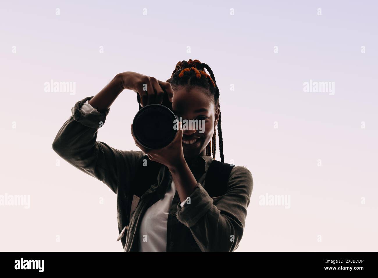 Jeune femme avec des tresses prenant une photo avec un appareil photo numérique, son passe-temps de la photographie brille à travers. Femme aventurière profitant d'un l heureux et amusant Banque D'Images