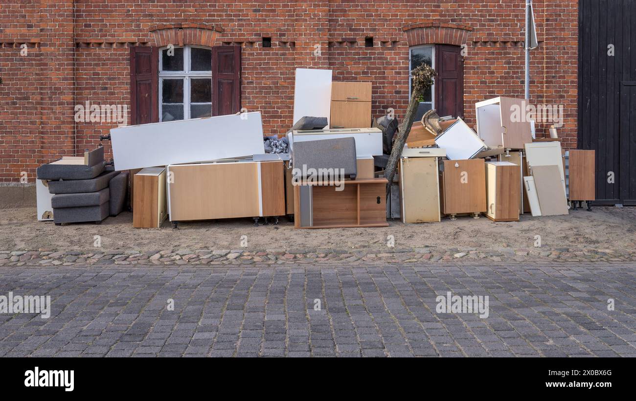 Pile de déchets encombrants avec des meubles sur le côté de la route devant une maison Banque D'Images