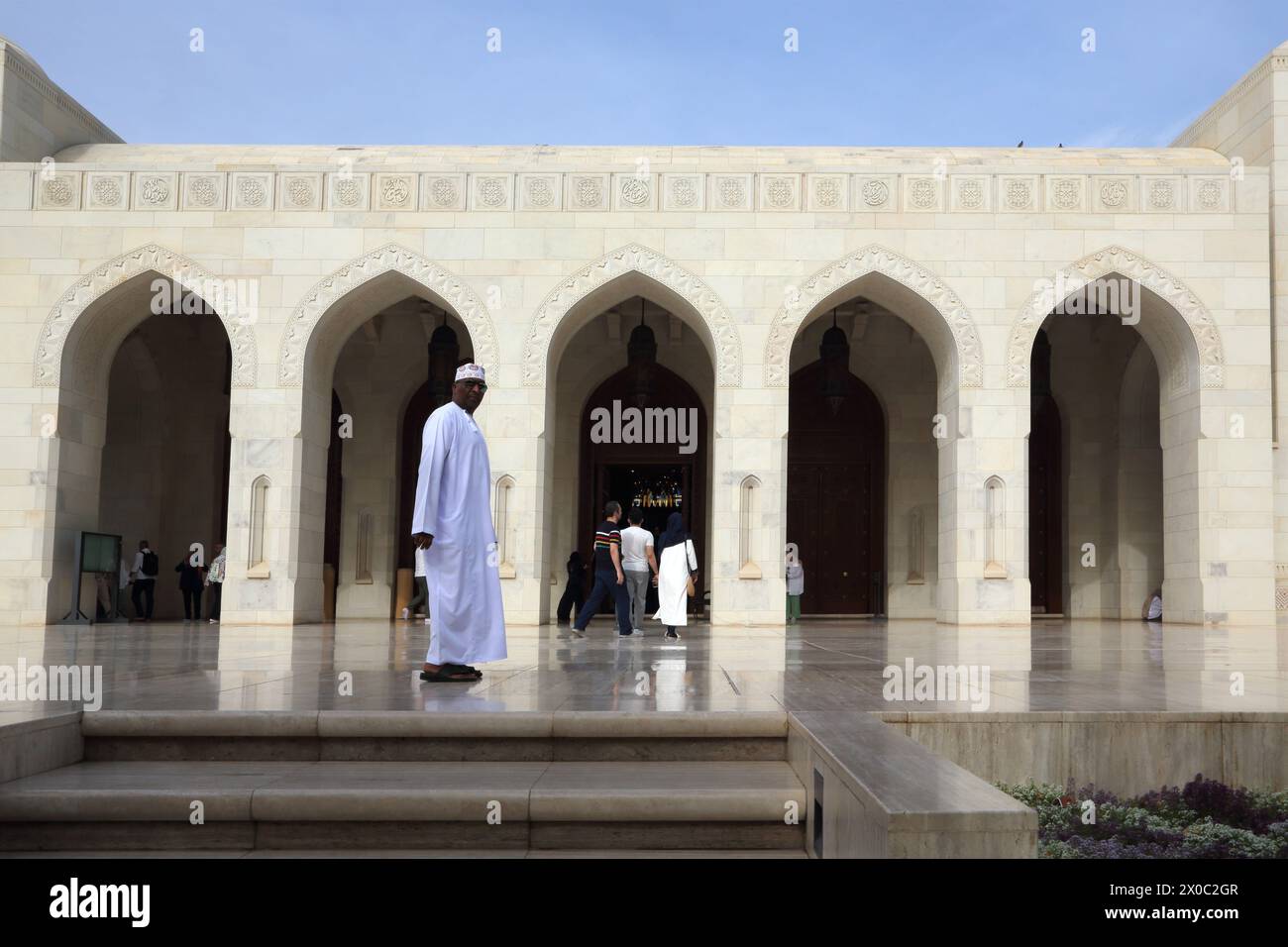 Sultan Qaboos Grande Mosquée omanaise habillé en Dishdasha et Kummah par l'Arcade (Riwaq) Muscat Oman Banque D'Images