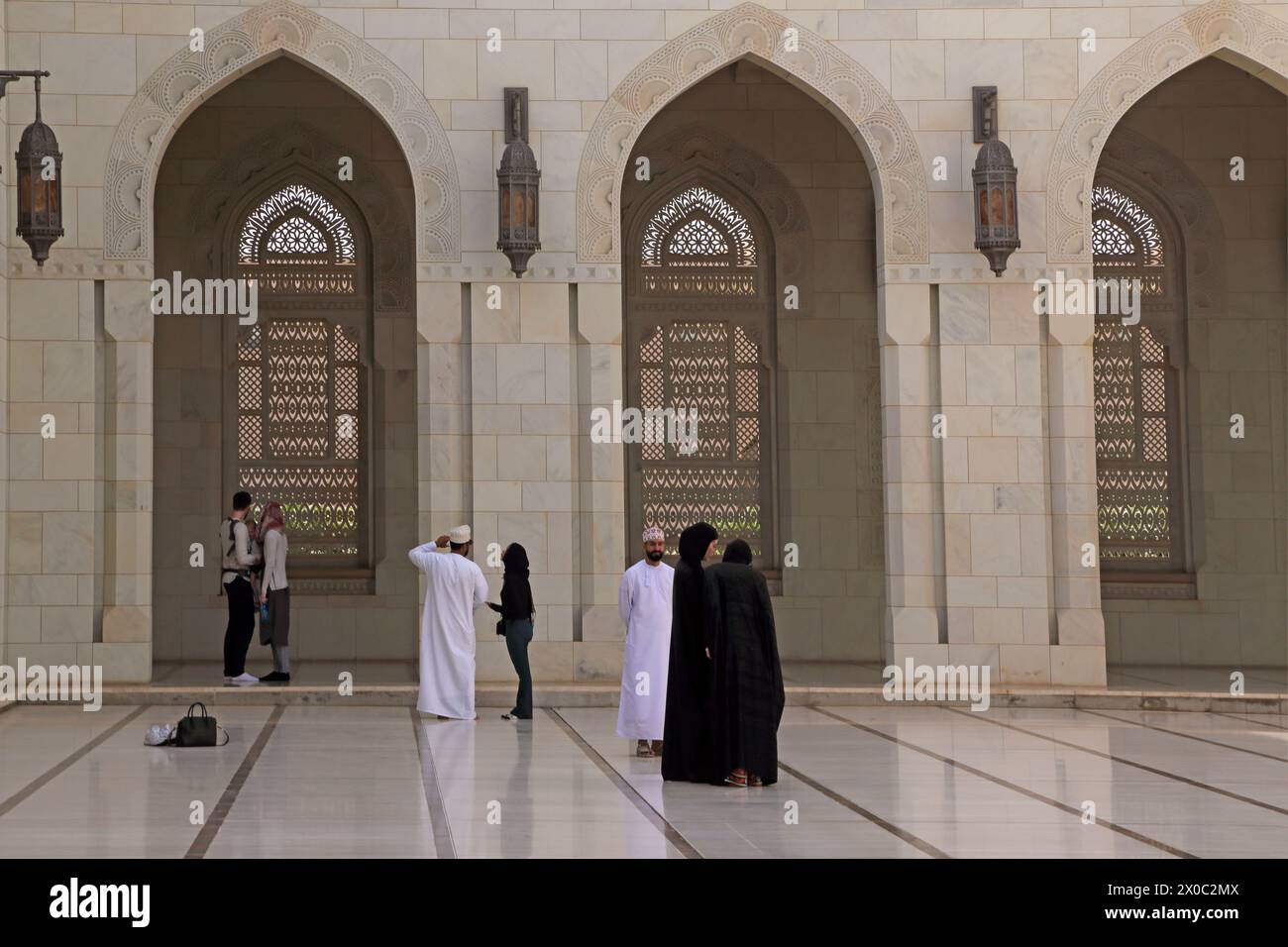 Sultan Qaboos Grand Mosquée visiteurs en robe occidentale et traditionnelle dans la cour (Sahn) Muscat Oman Banque D'Images