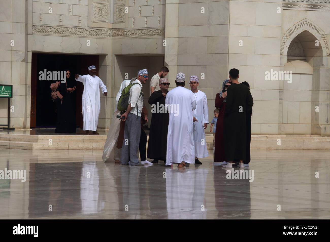 Guide touristique de la Grande Mosquée du sultan Qaboos avec des touristes à Courtyard (Sahn) Muscat Oman Banque D'Images