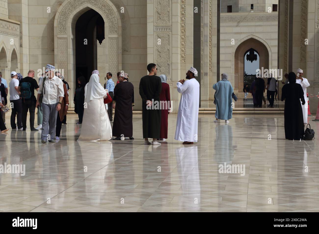 Guide touristique de la Grande Mosquée du sultan Qaboos avec des touristes à Courtyard (Sahn) Muscat Oman Banque D'Images