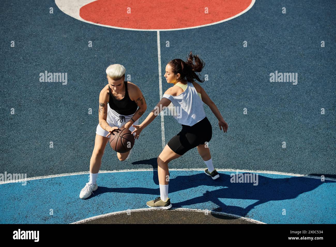 Deux femmes athlétiques se tiennent en toute confiance sur un terrain de basket-ball, prêtes à relever tous les défis qui se présentent à elles. Banque D'Images