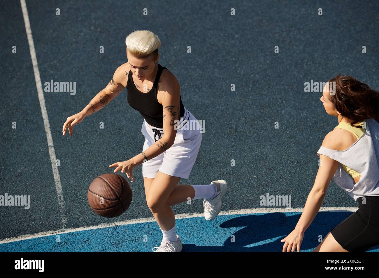 Un match intense de basket-ball entre deux jeunes femmes, des amies mettant en valeur leurs compétences athlétiques sur le terrain extérieur en été. Banque D'Images