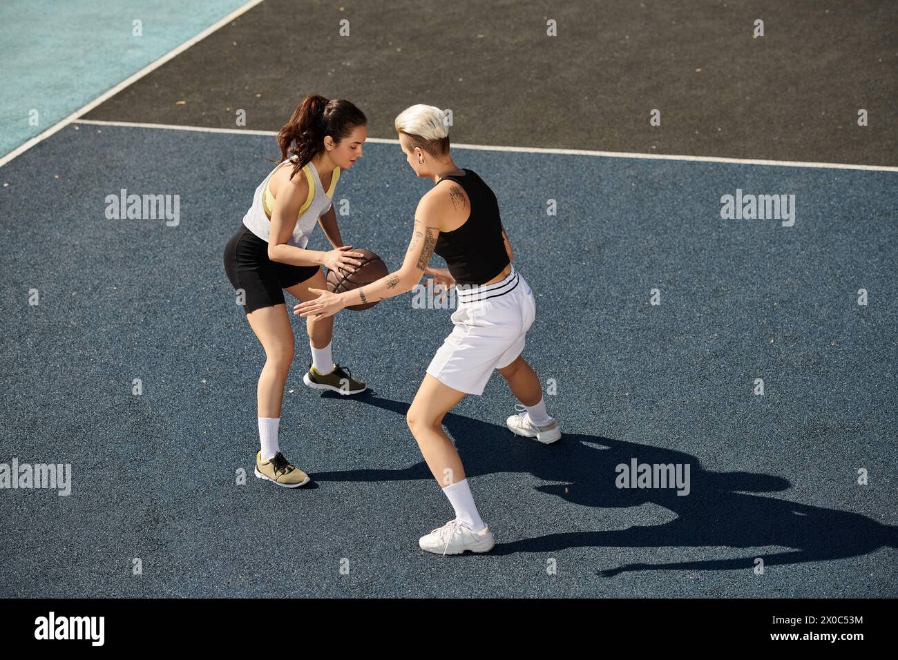 Deux femmes athlétiques se tiennent triomphalement au sommet d'un court de tennis, prêtes à affronter n'importe quel adversaire. Banque D'Images