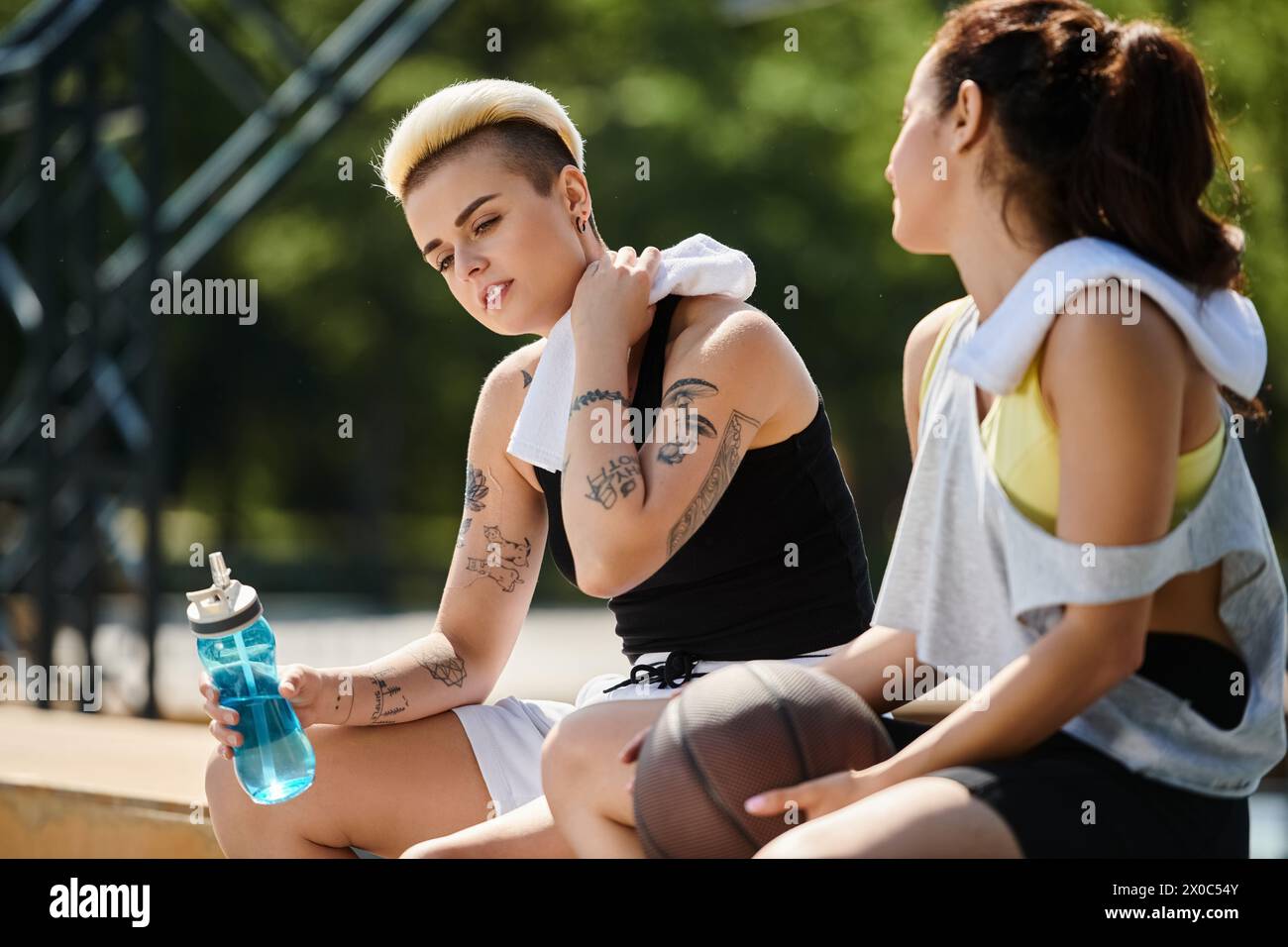Deux jeunes femmes, athlétiques et animées, profitent d'une partie de basket-ball en plein air par une journée ensoleillée d'été. Banque D'Images