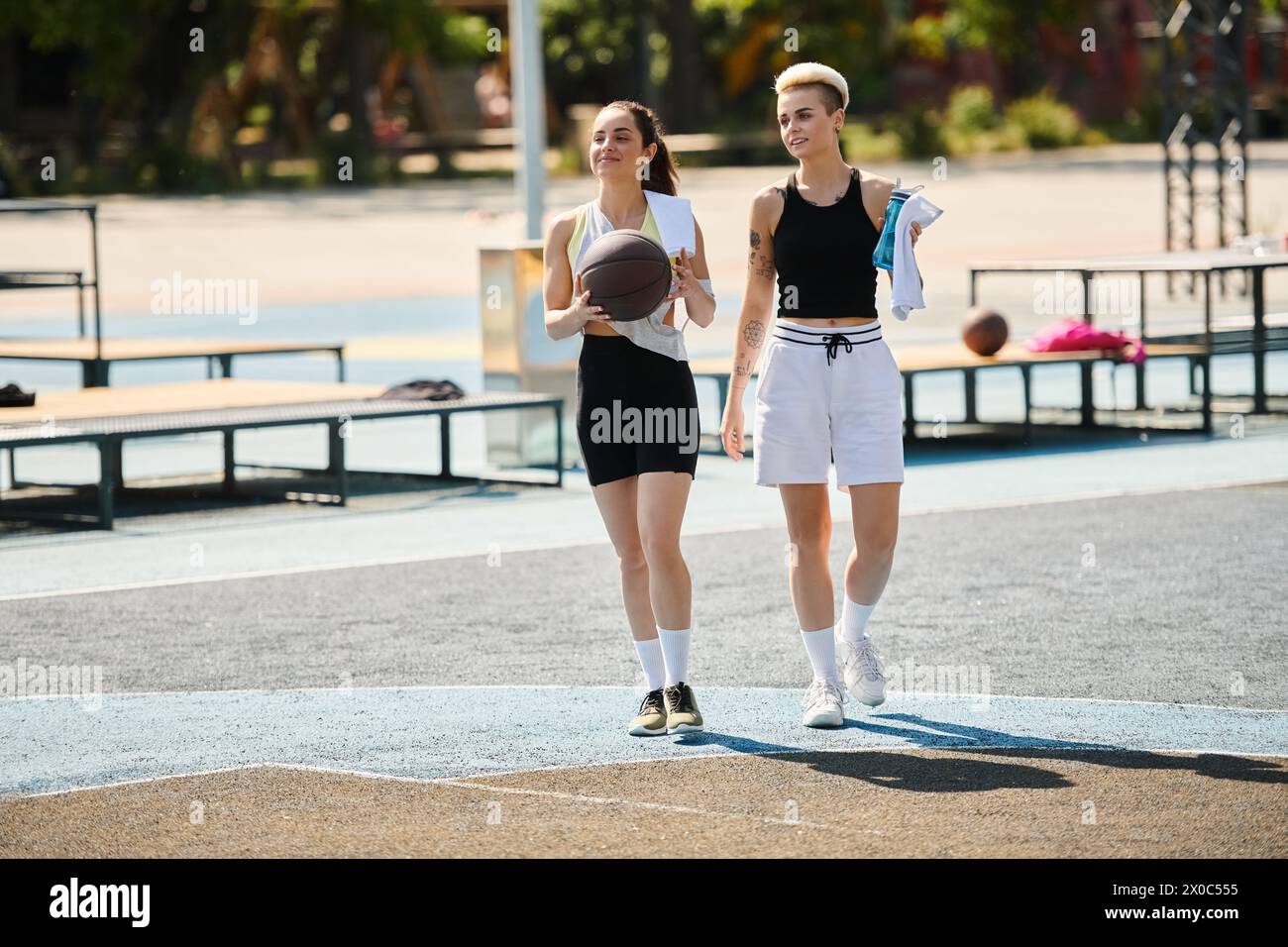 Deux amies athlétiques conquièrent le terrain de basket-ball par une journée d'été ensoleillée. Banque D'Images