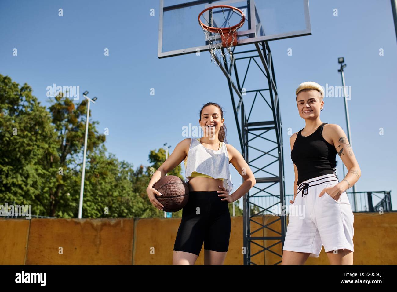 Deux jeunes femmes athlétiques jouant au basket-ball par un cerceau en plein air par une journée ensoleillée. Banque D'Images