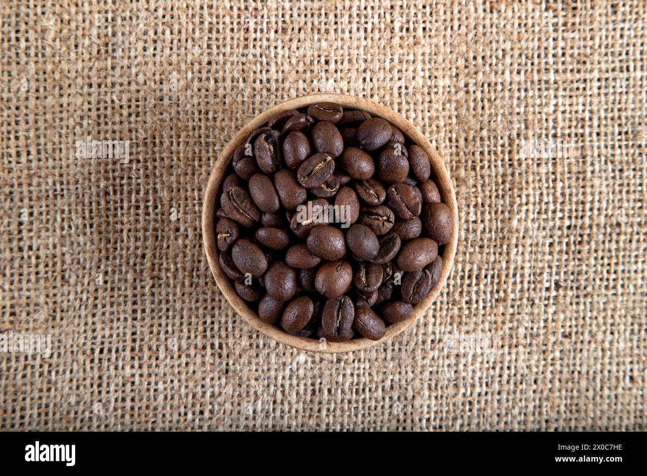 Gros plan de grains de café torréfiés sur toile de jute, vue de dessus Banque D'Images