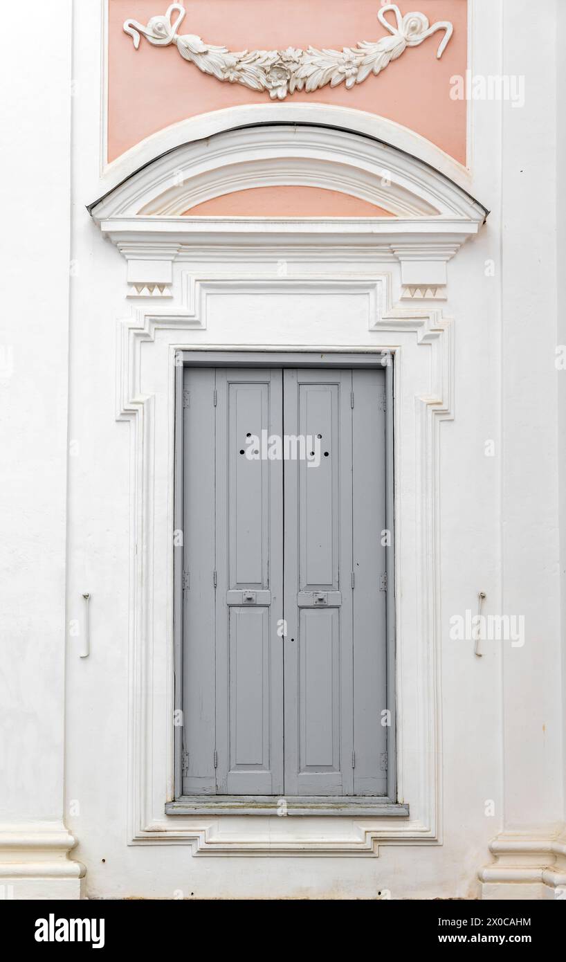 Porte en bois gris fermée dans le mur rose blanc, texture de photo de fond vertical. Détails architecturaux classiques Banque D'Images